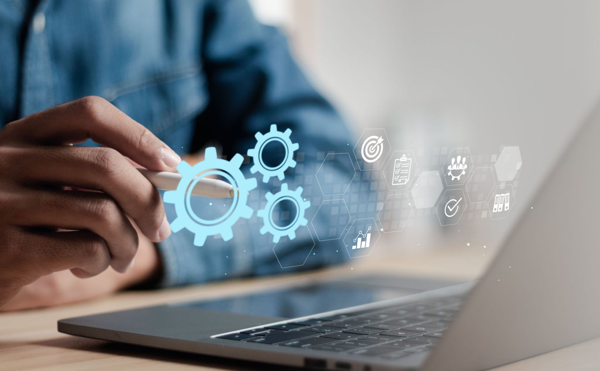 Person using a laptop with holographic gear and business icons representing technology and productivity.